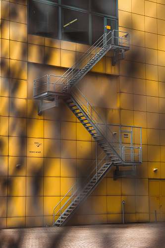 the hague gray steel ladder beside yellow building fire stair